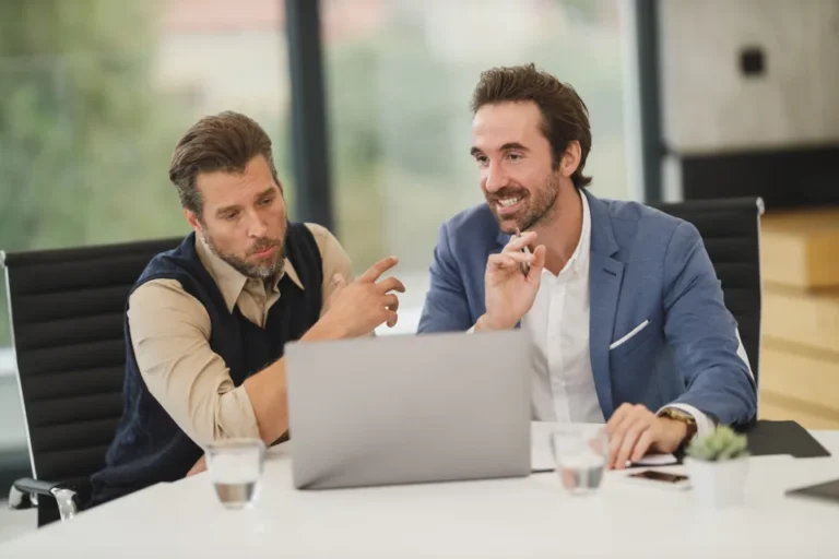 Small business team discussing workplace AI guidelines around a laptop in a meeting room