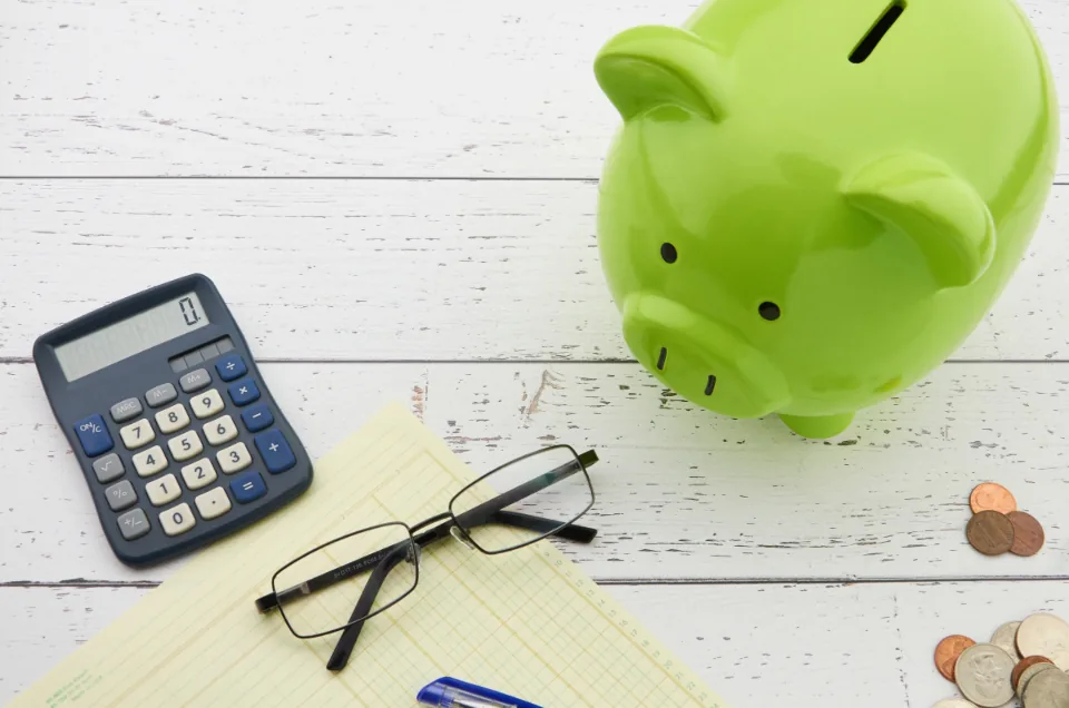 Freelancer planning a savings budget with a notebook and laptop at a home office desk
