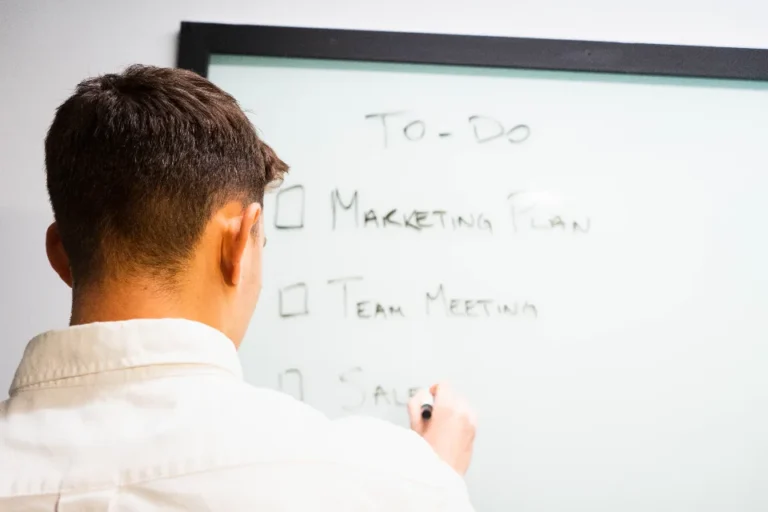 Two startup founders planning business priorities on a whiteboard in a small office