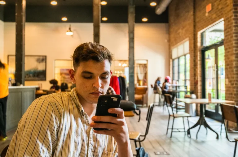 Business owner approving a login with a two-factor authentication app on a smartphone next to a laptop